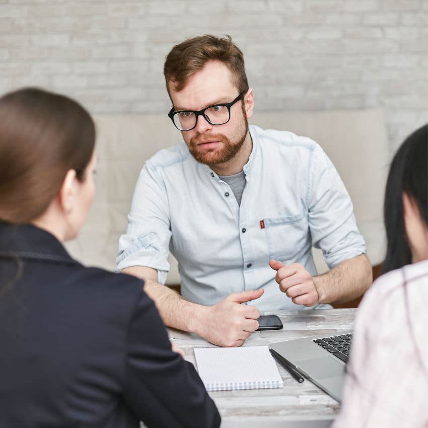 Man speaking aggressively during a workplace discussion while his coworkers seem uncomfortable and intimidated