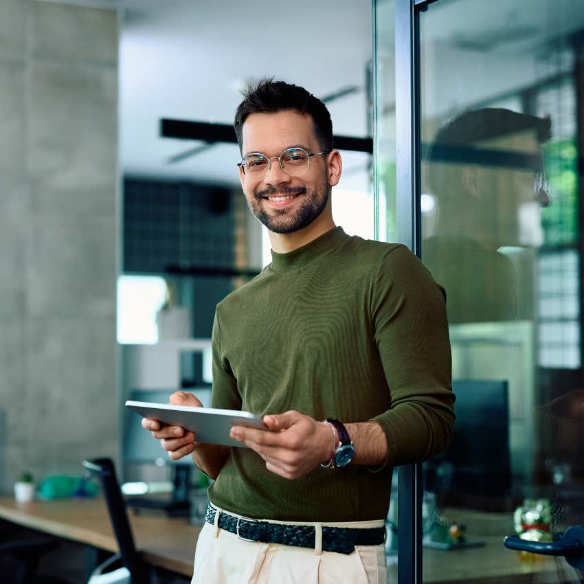 millennial man on ipad smiling happily at work