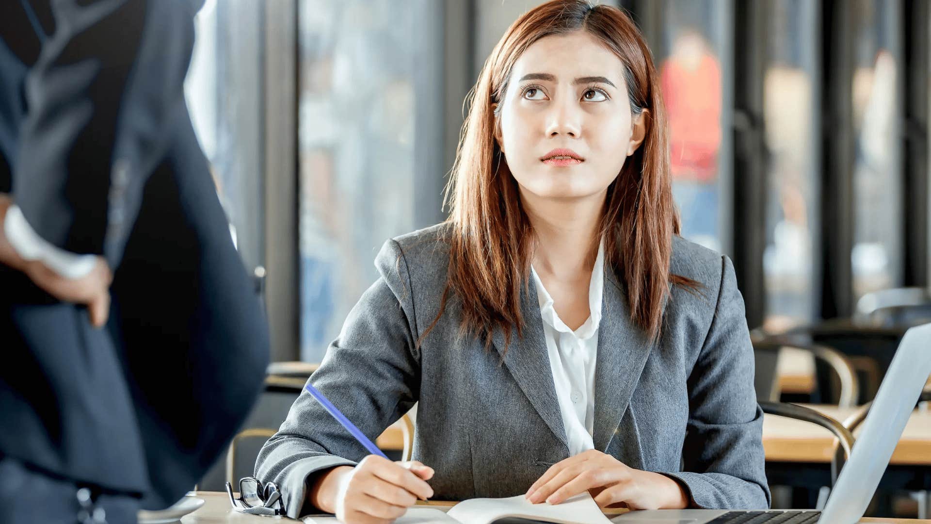 millennial woman at work listening to boss micromanage her