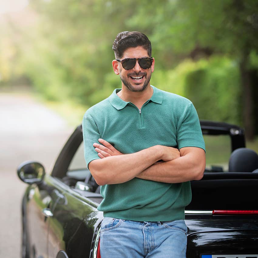 man leaning up against sports car he bought to solve his problems