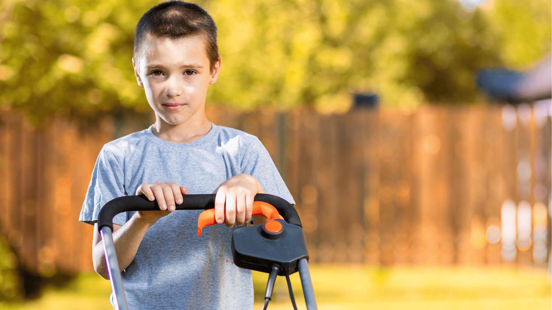 little boy mowing the lawn at home