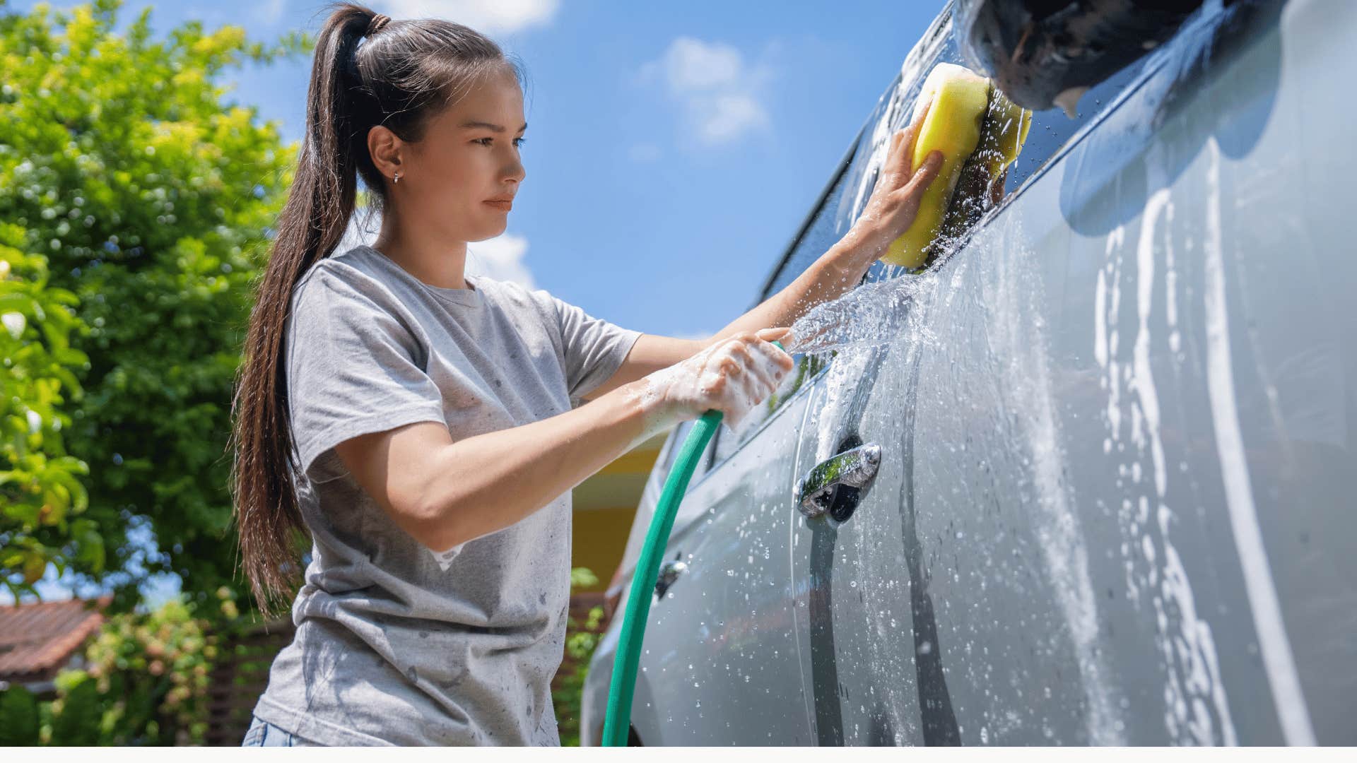 girl washing her parents' car by hand in the driveway