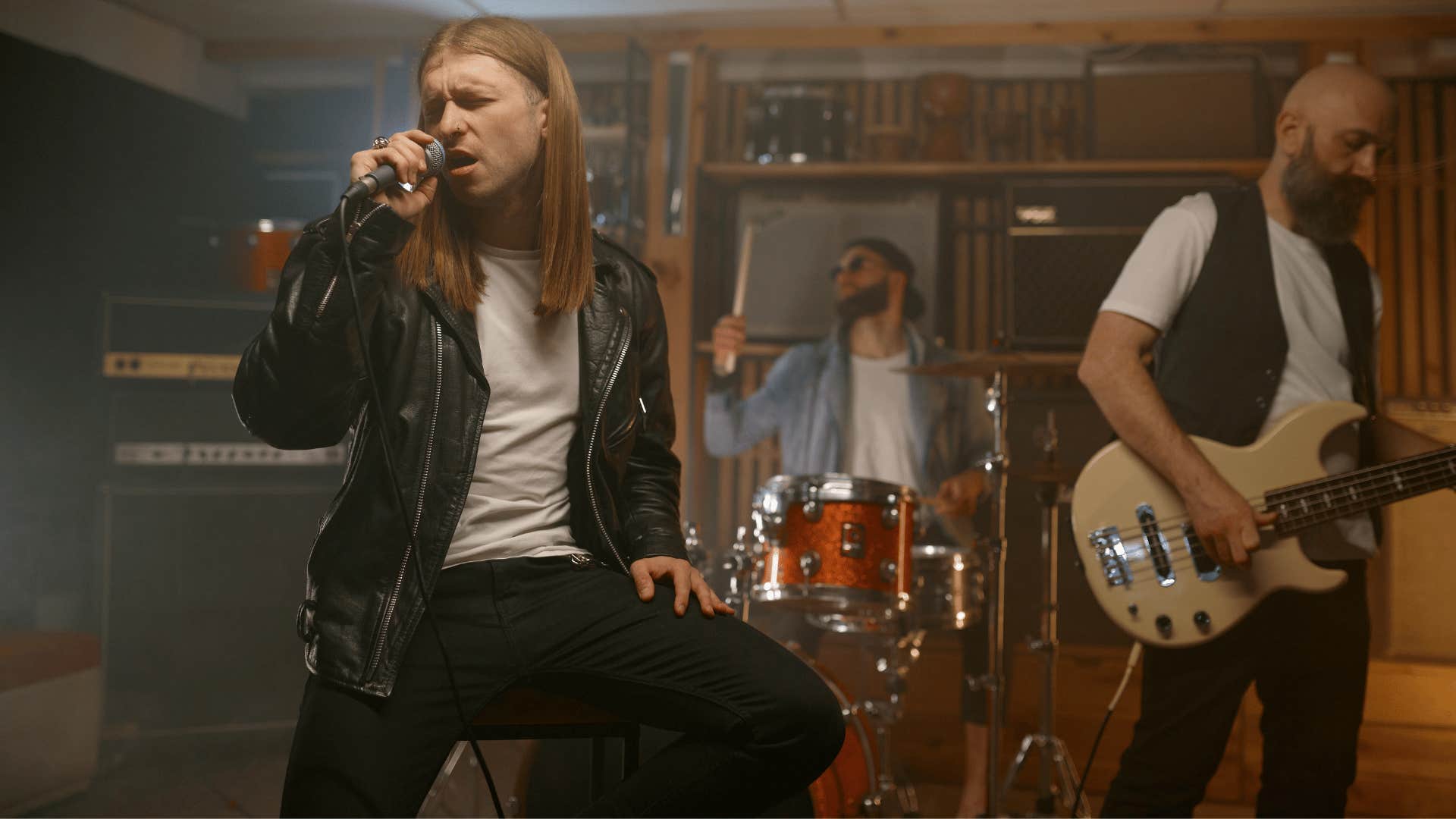 man in leather jacket singing as he's in a garage band