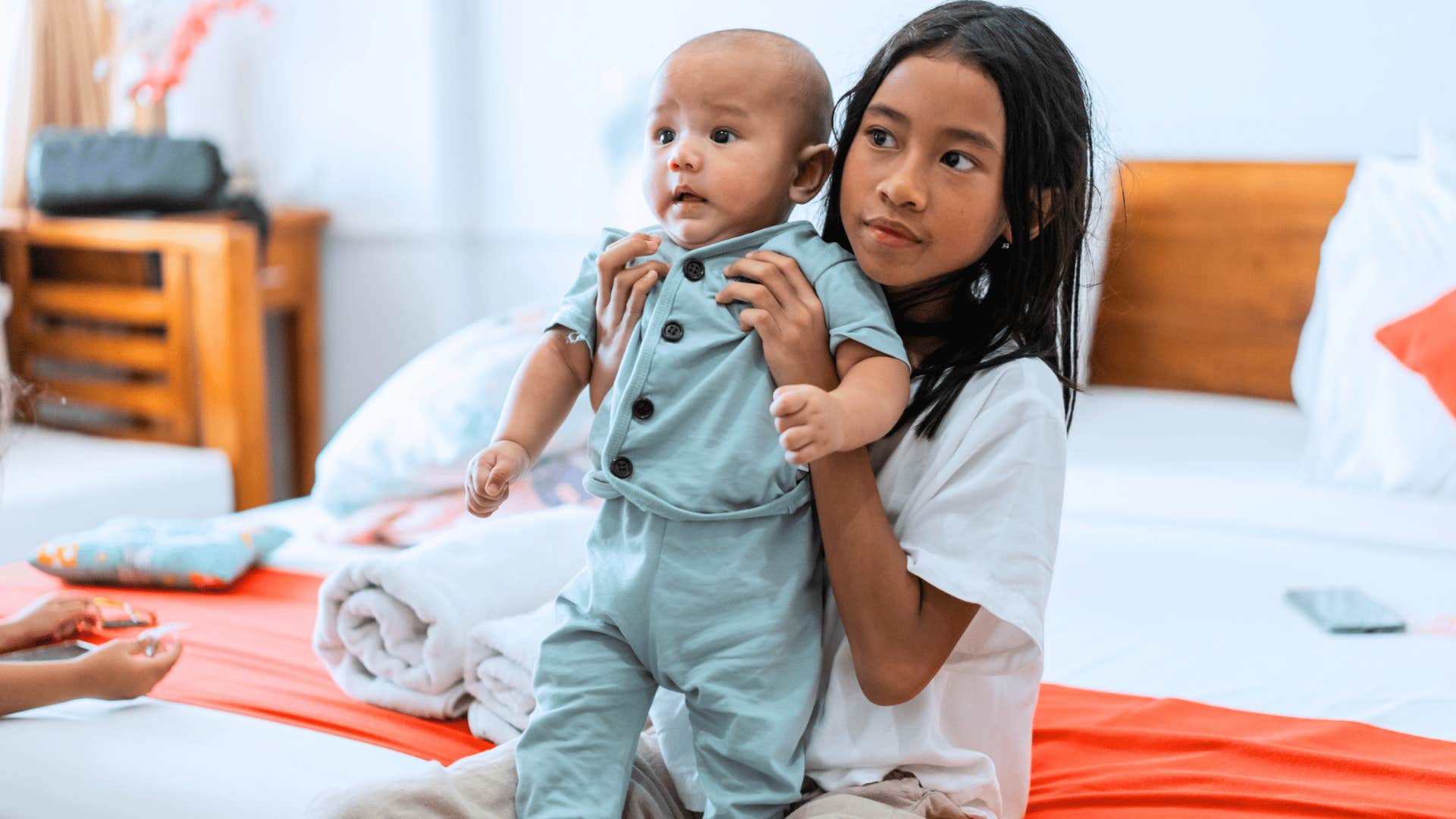 little girl holding her sibling in a home where gender roles apply