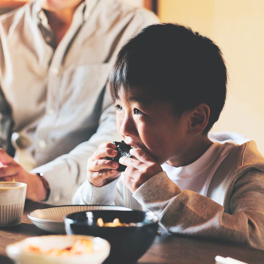 Little boy practicing dinner etiquette with his family.