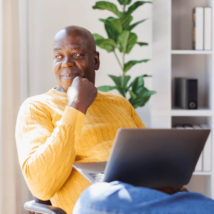 older gentleman holding an open laptop