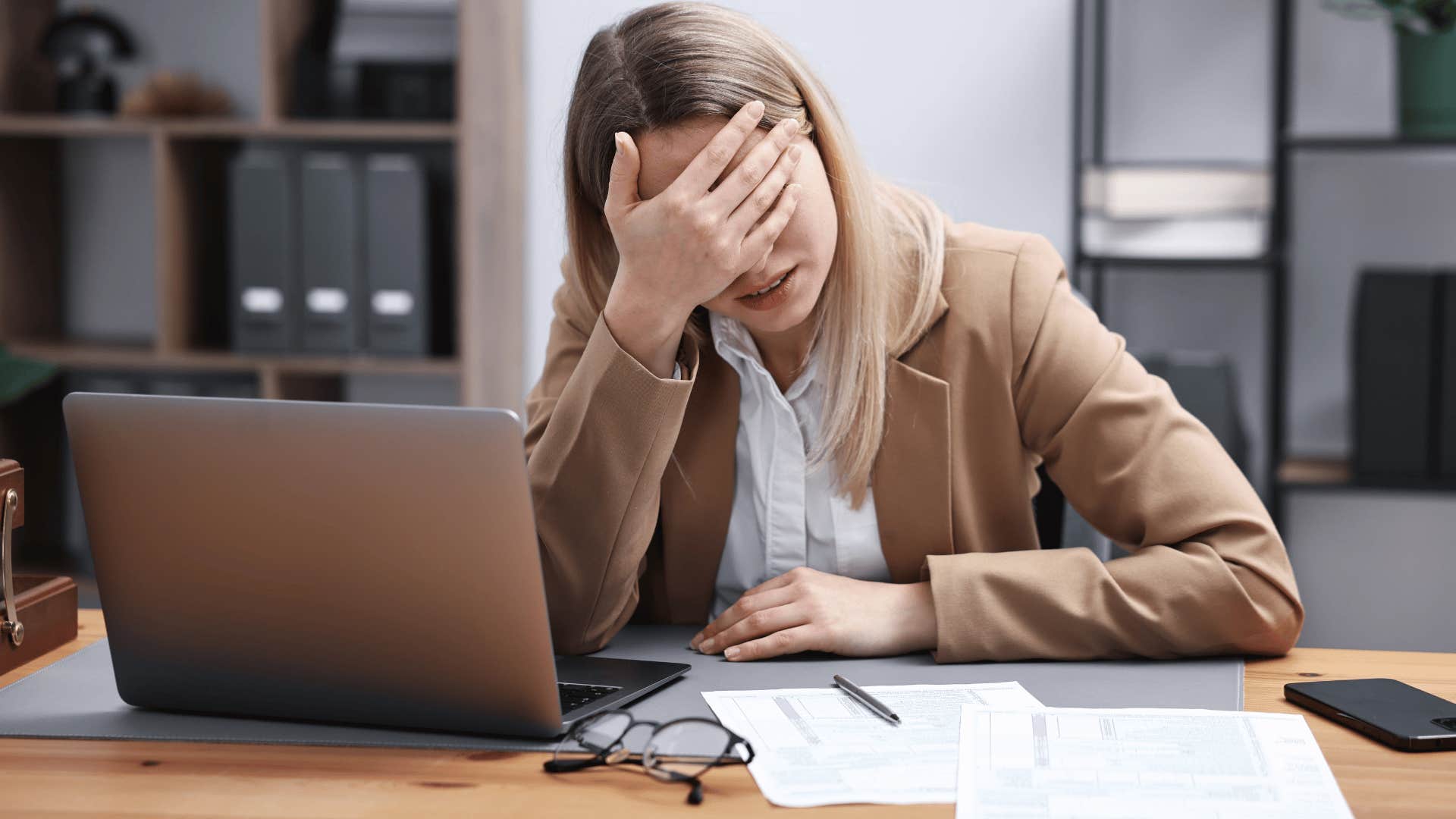 woman in brown jacket face palming at work as she thinks i'm too tired