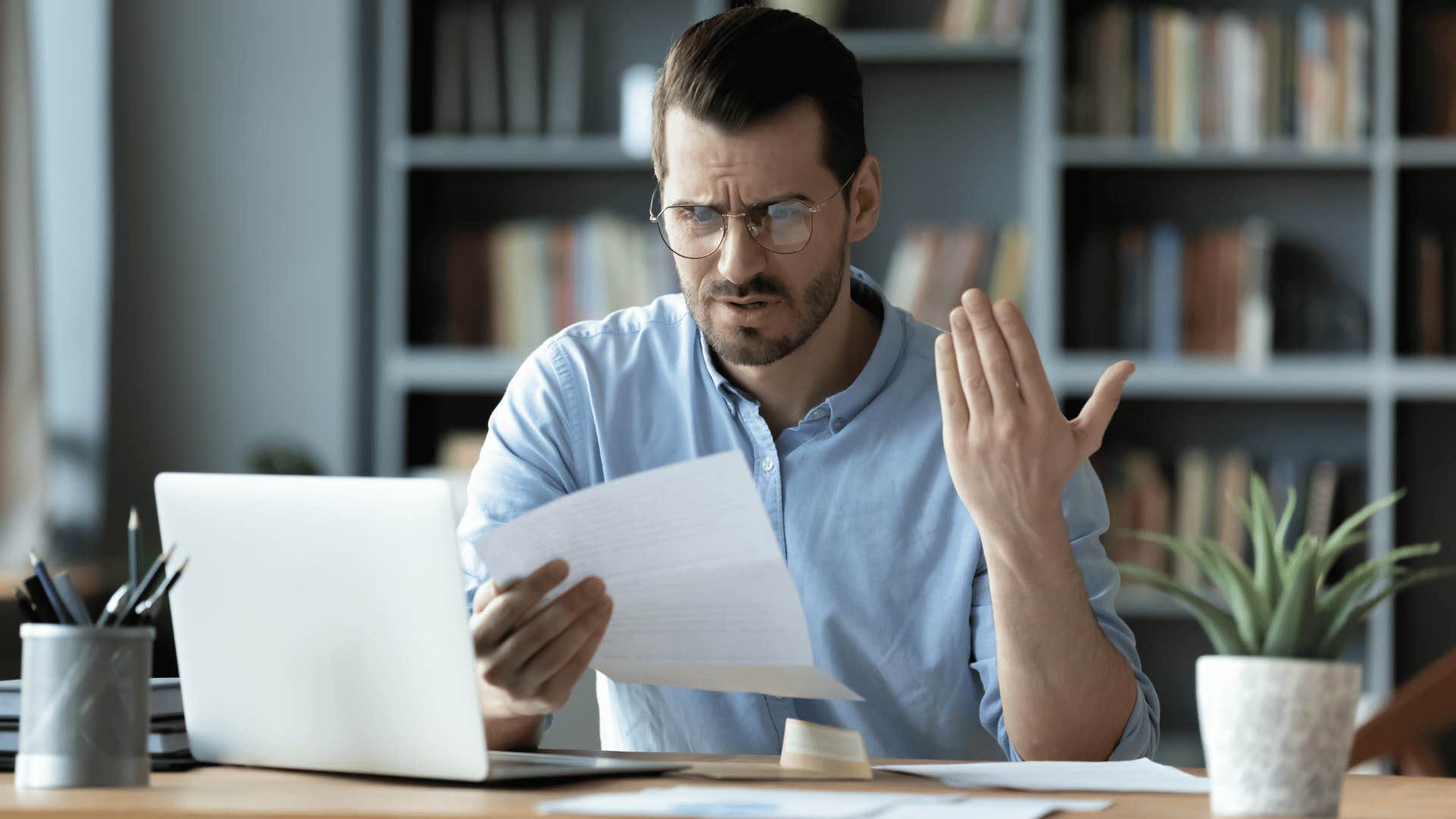 man in blue shirt upset looking at document as he thinks it's too much work