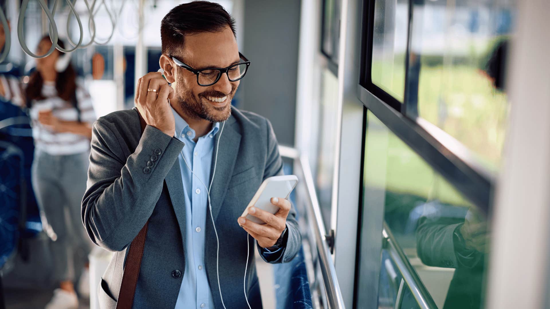 man in glasses on bus as he's happy listening to podcasts