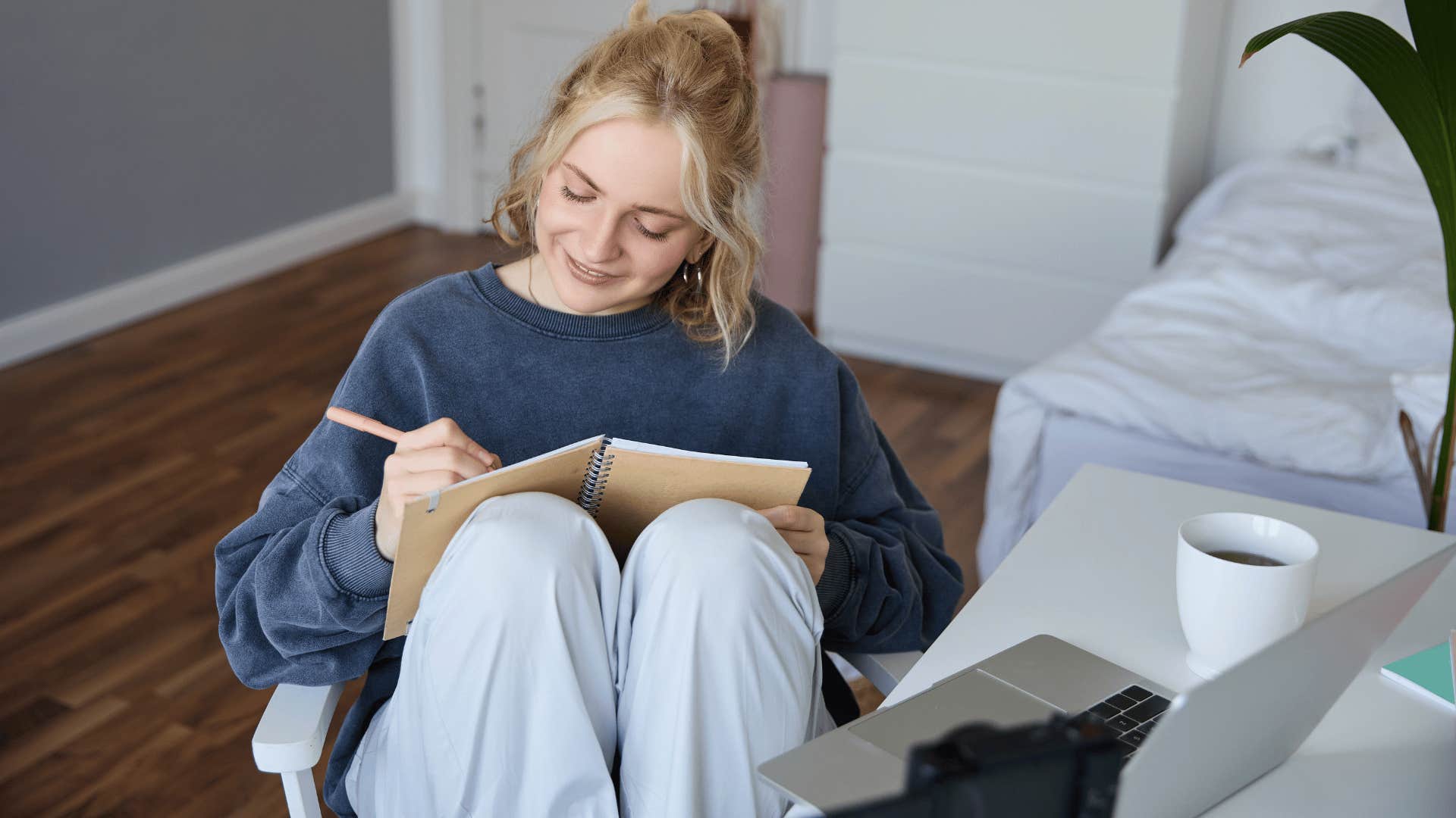 woman in blue shirt writing new stories and poems in her bedroom 