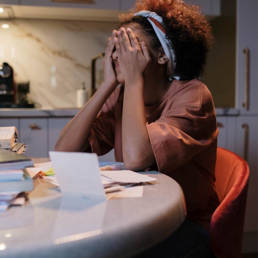 Woman sitting at a kitchen table with overdue bills believing one financial mistake has permanently damaged her future