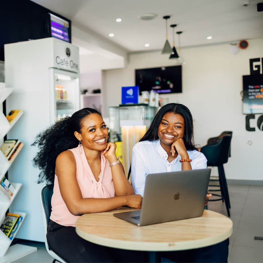 Two co-workers smiling after an encouraging conversation that leaves one person feeling happier and more confident