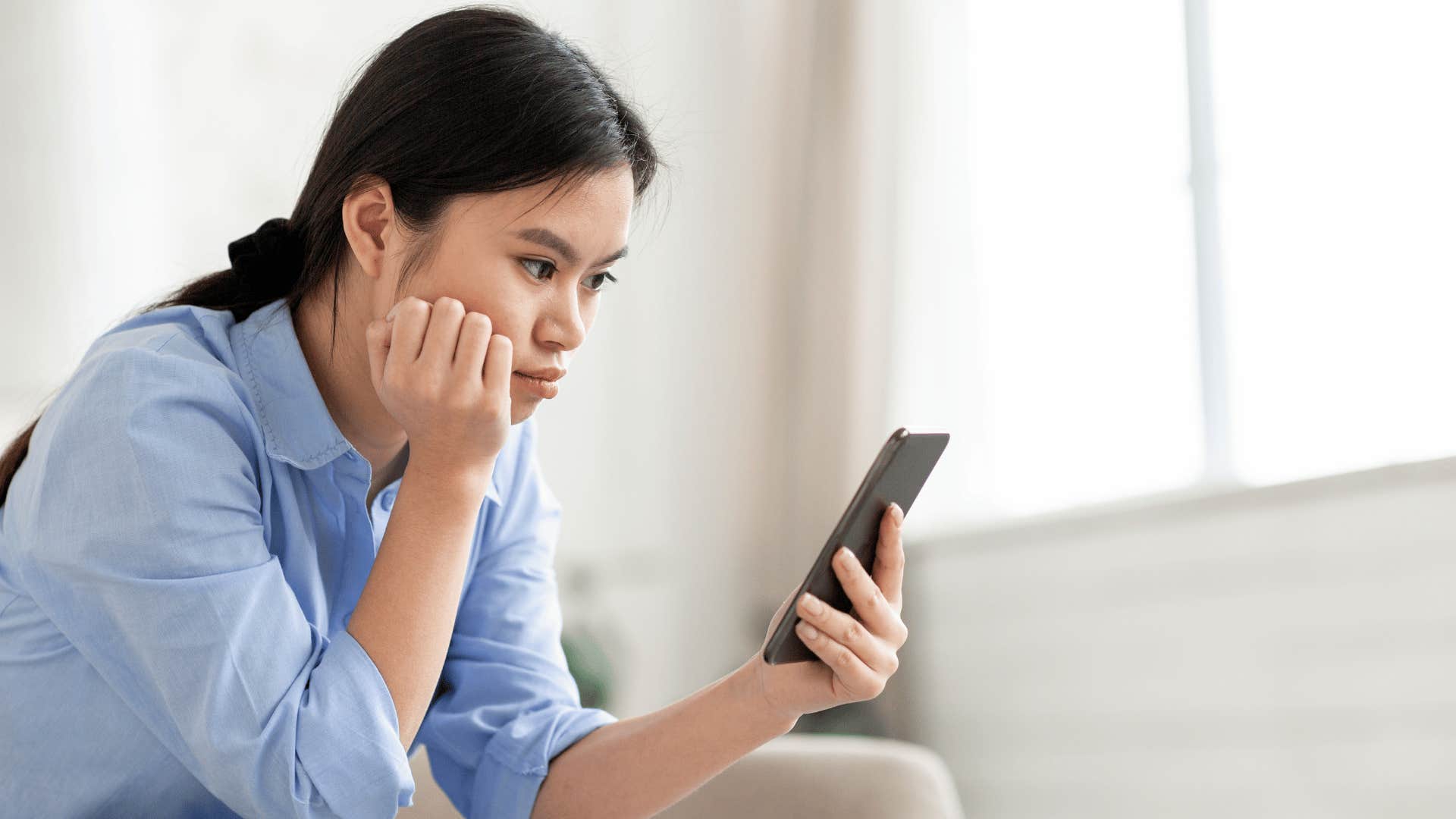 woman looking at messages but refusing to respond due to her sadness