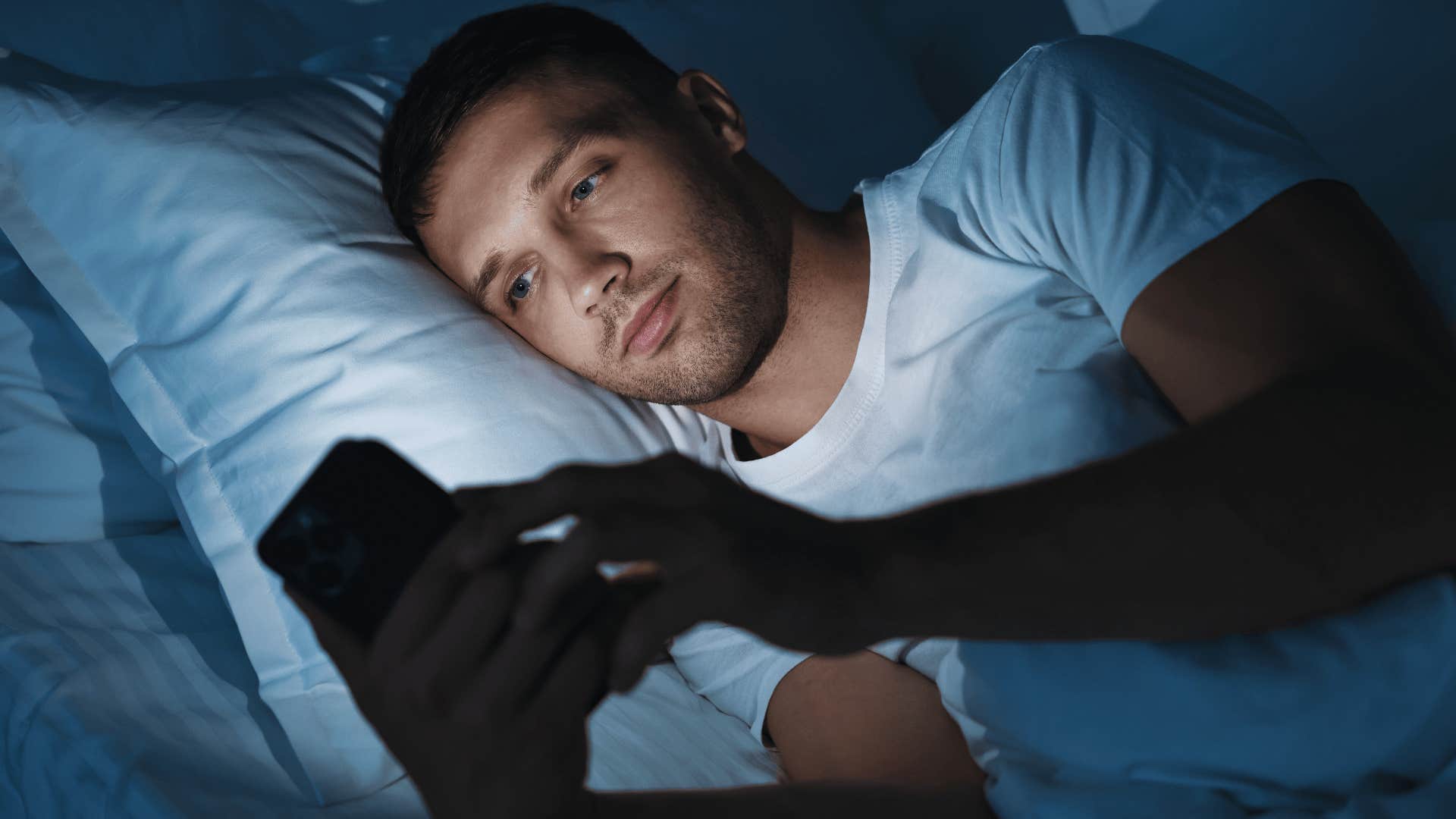 man scrolling in bed staying up too late