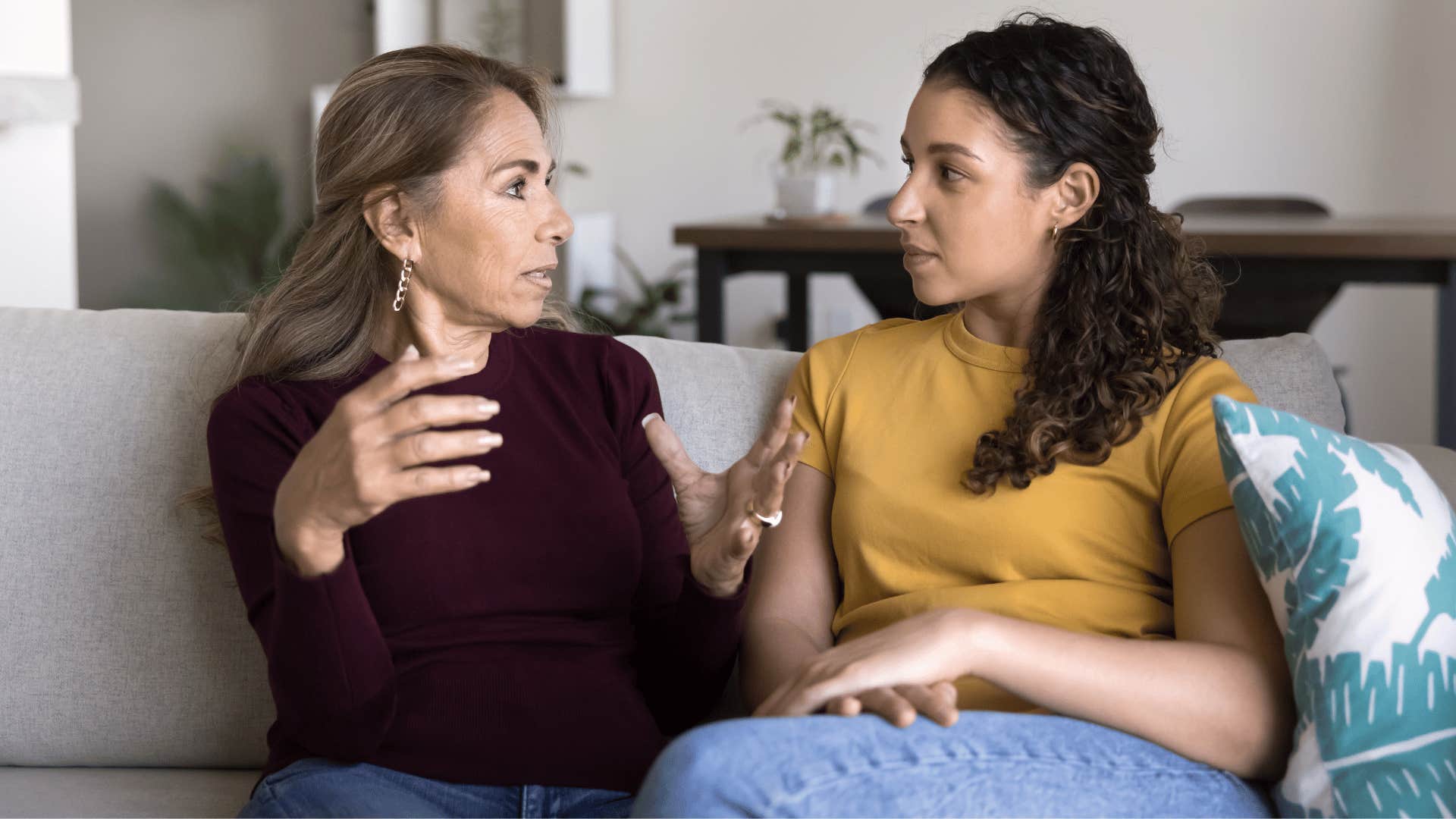 older woman in red shirt telling daughter i can agree to disagree as they sit on couch