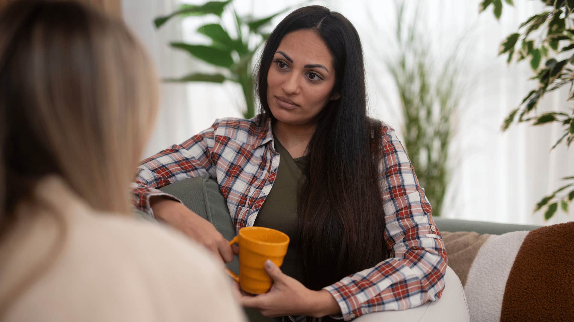 woman in plaid shirt listening to woman as she says can you help me understand