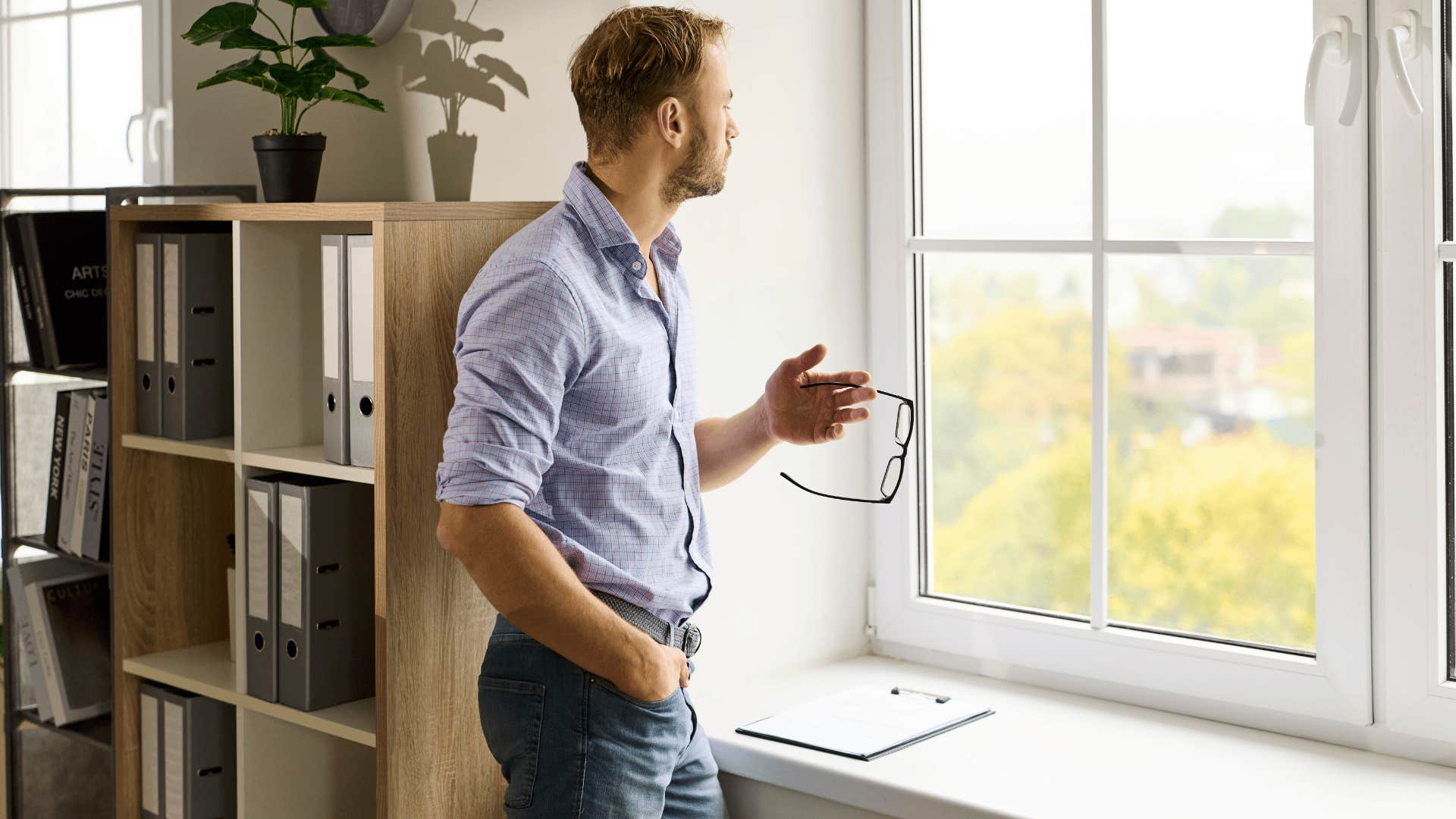 man looking out the window as he thinks i need a little more time to think about that