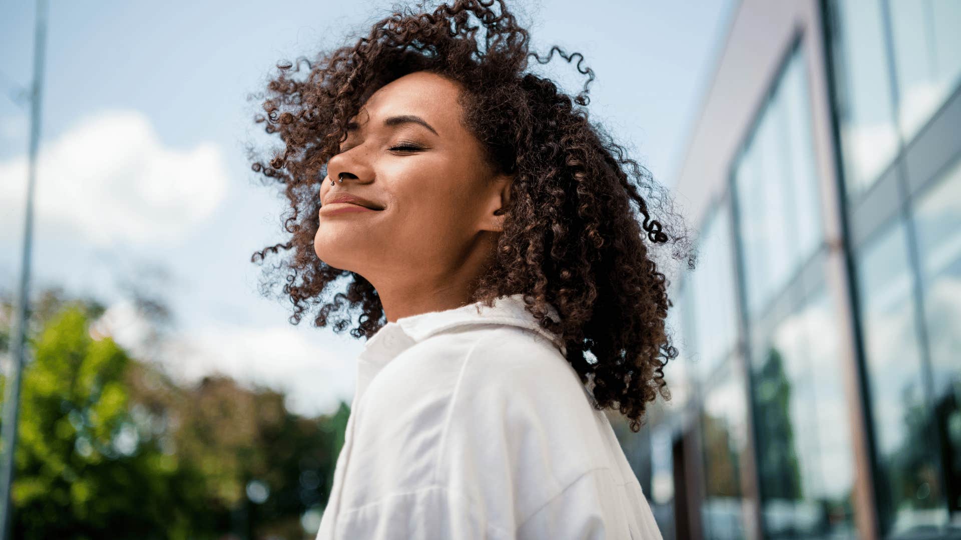 woman in white shirt smiling brightly as she thinks i don't care what anyone thinks