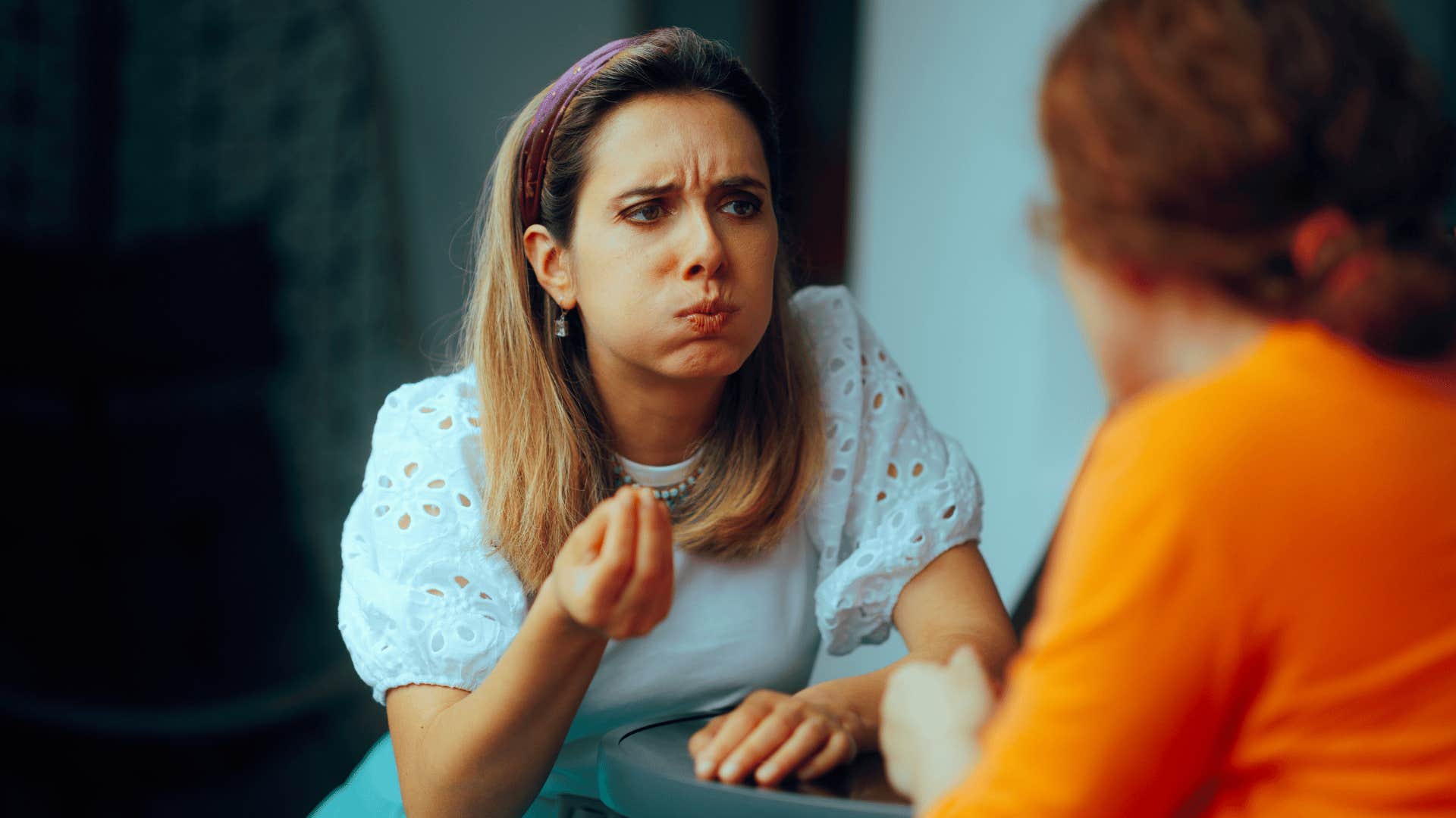 woman in white shirt looking fed up as she tells friend it's not that deep