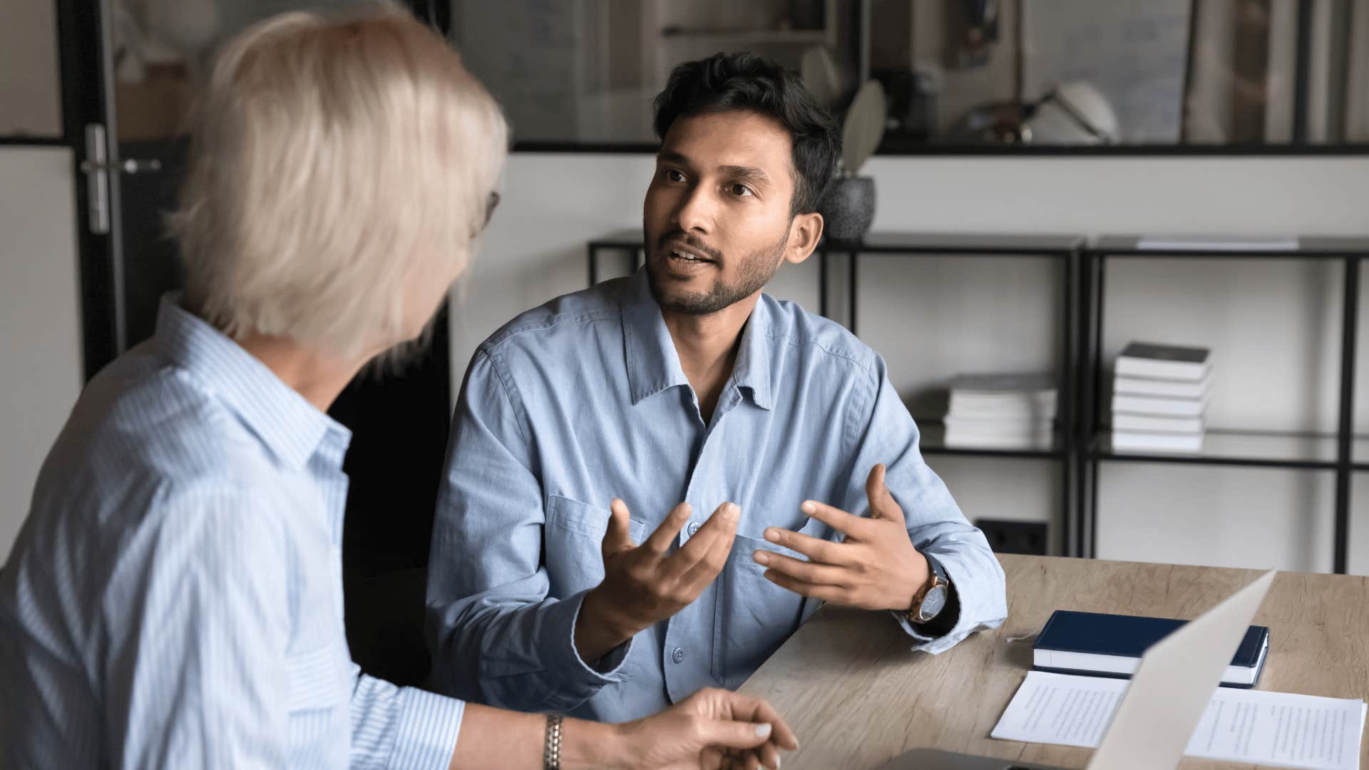 man in blue shirt talking to coworker as he says i already know how this works