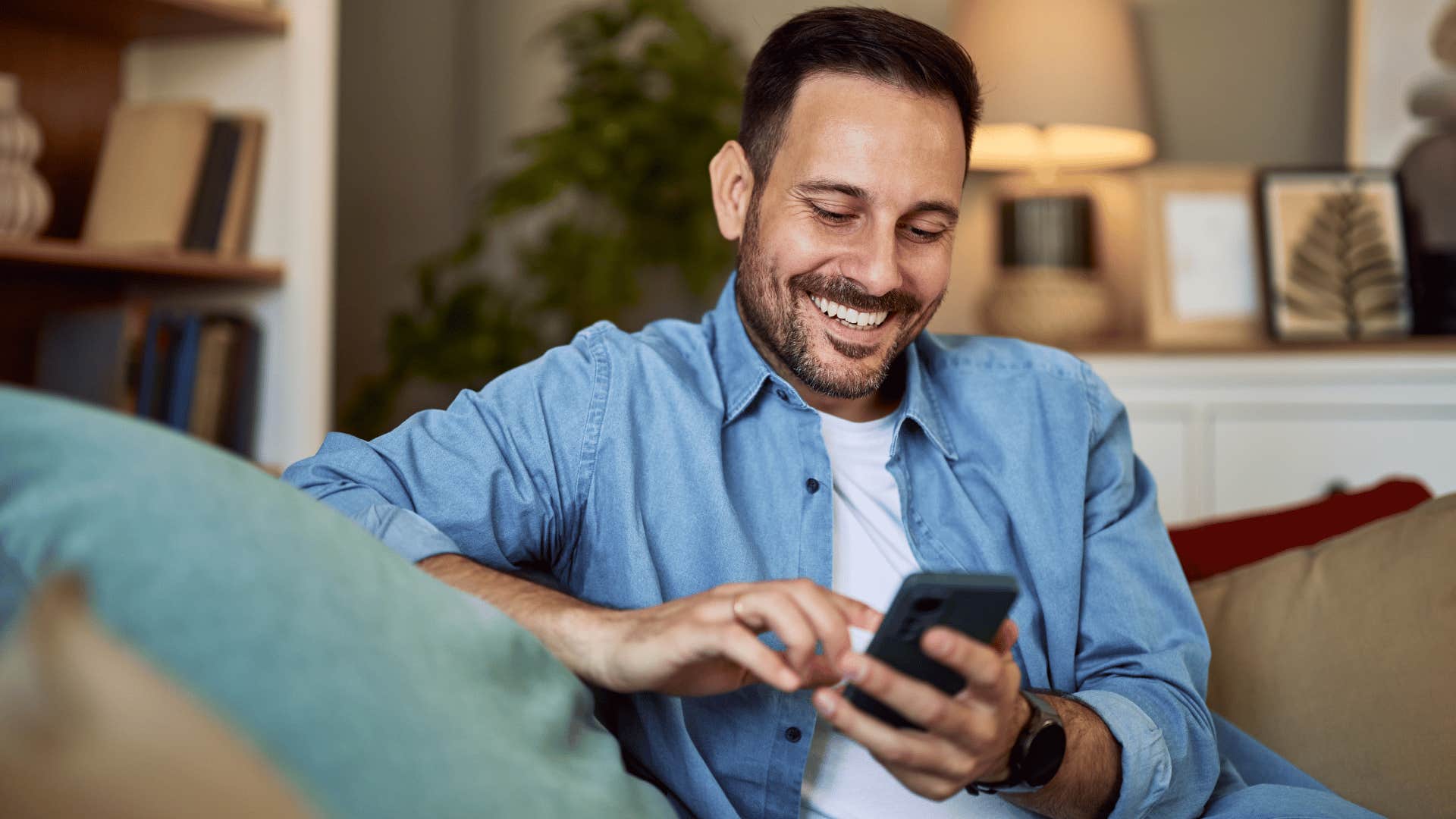man smiling while adding friend to group chat on his phone