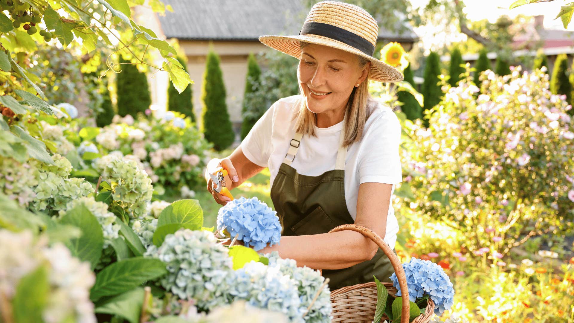 woman in white shirt and brown apron smiling brightly while gardening