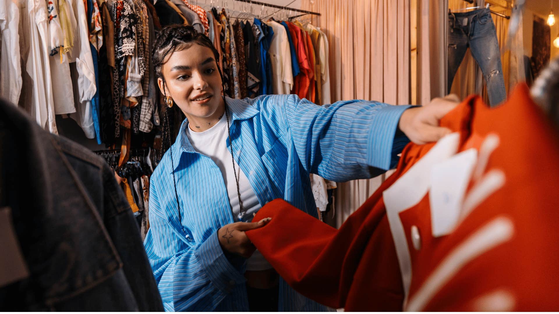 woman in blue jean jacket going thrifting as she looks through clothes
