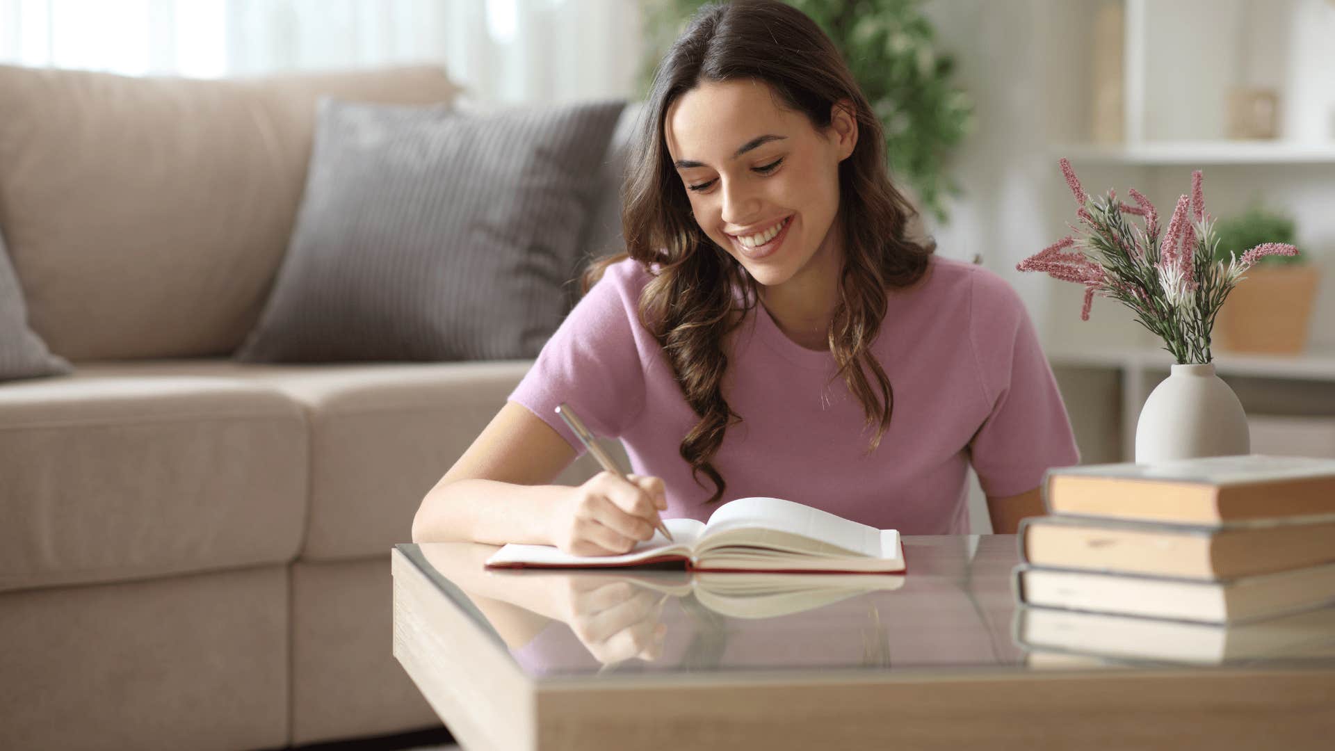 woman in pink shirt journaling to process their thoughts and emotions