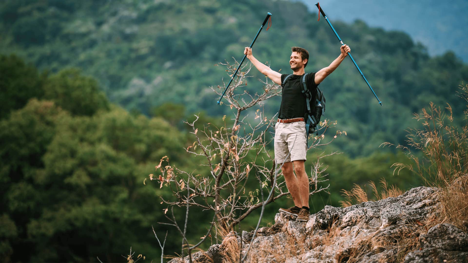 man in black shirt cheering as he goes solo hiking