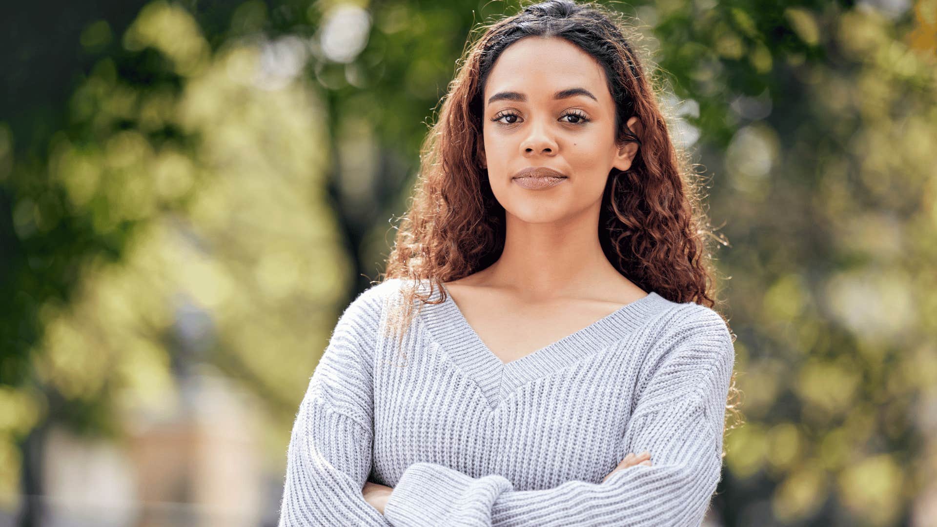 woman in gray sweater crossing arms defensively as she thinks i don't owe anyone anything