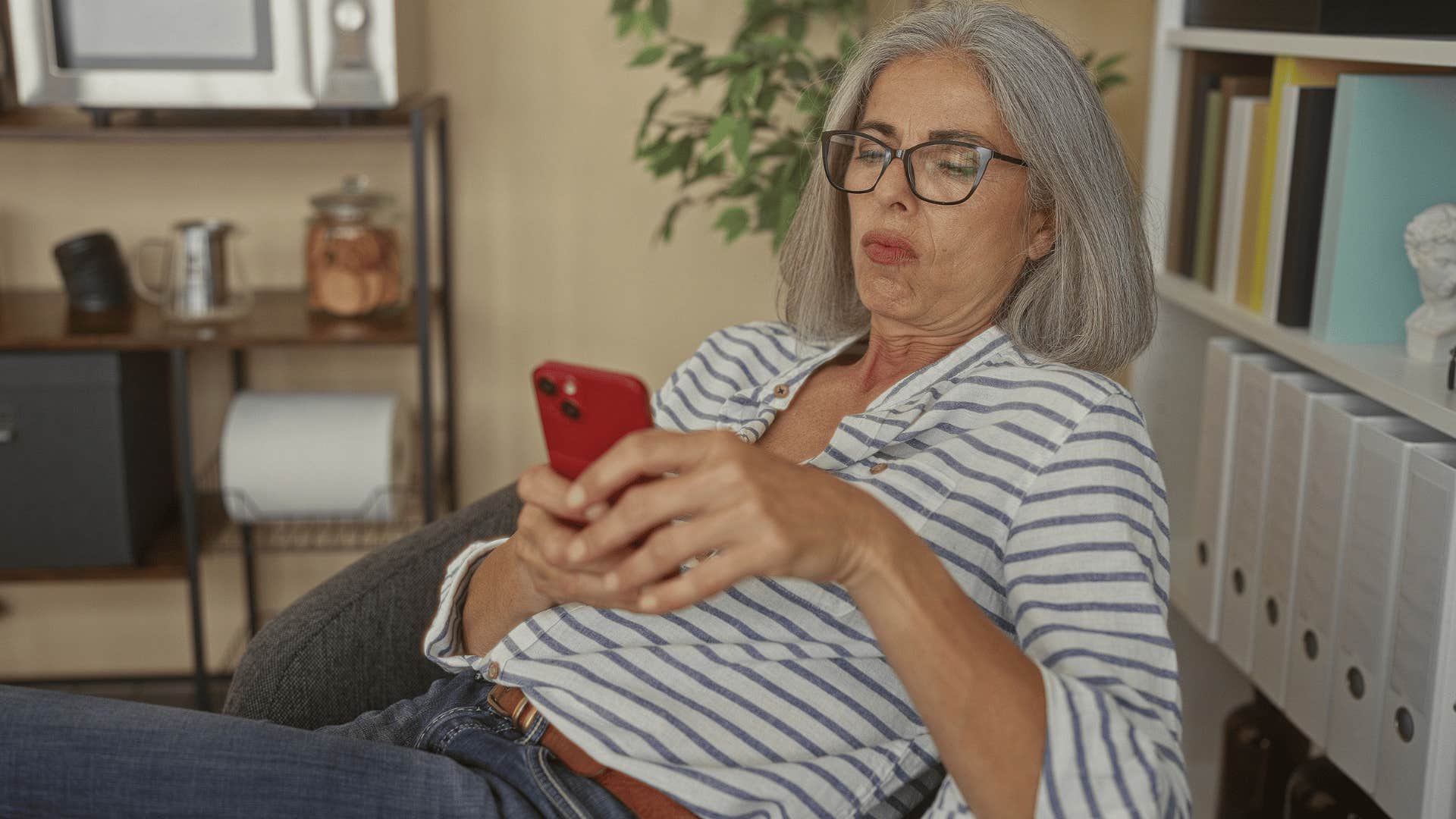 woman with stripped shirt on phone scrolling and thinking must be nice
