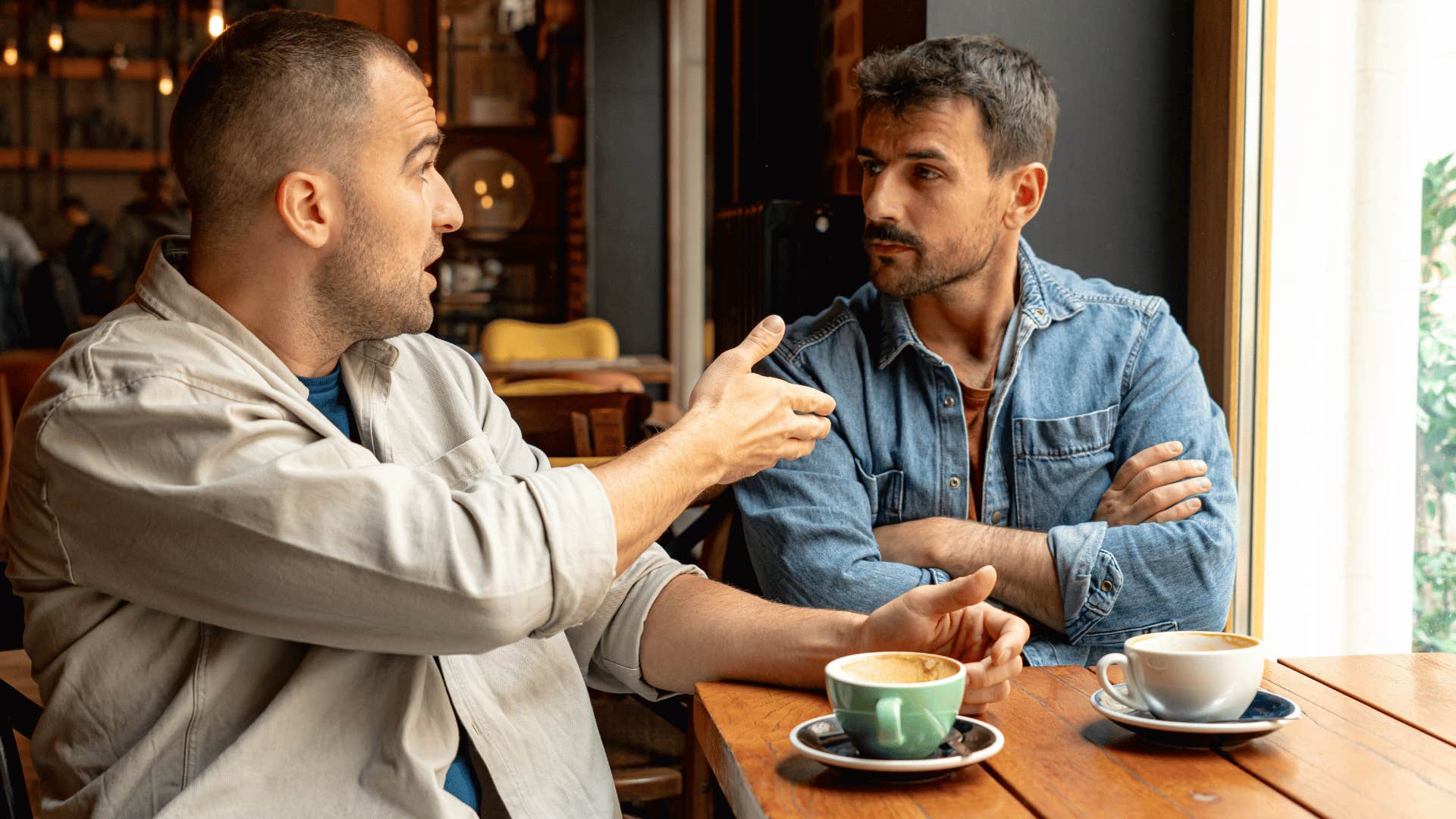 man talking to friend at cafe as he says that's their problem