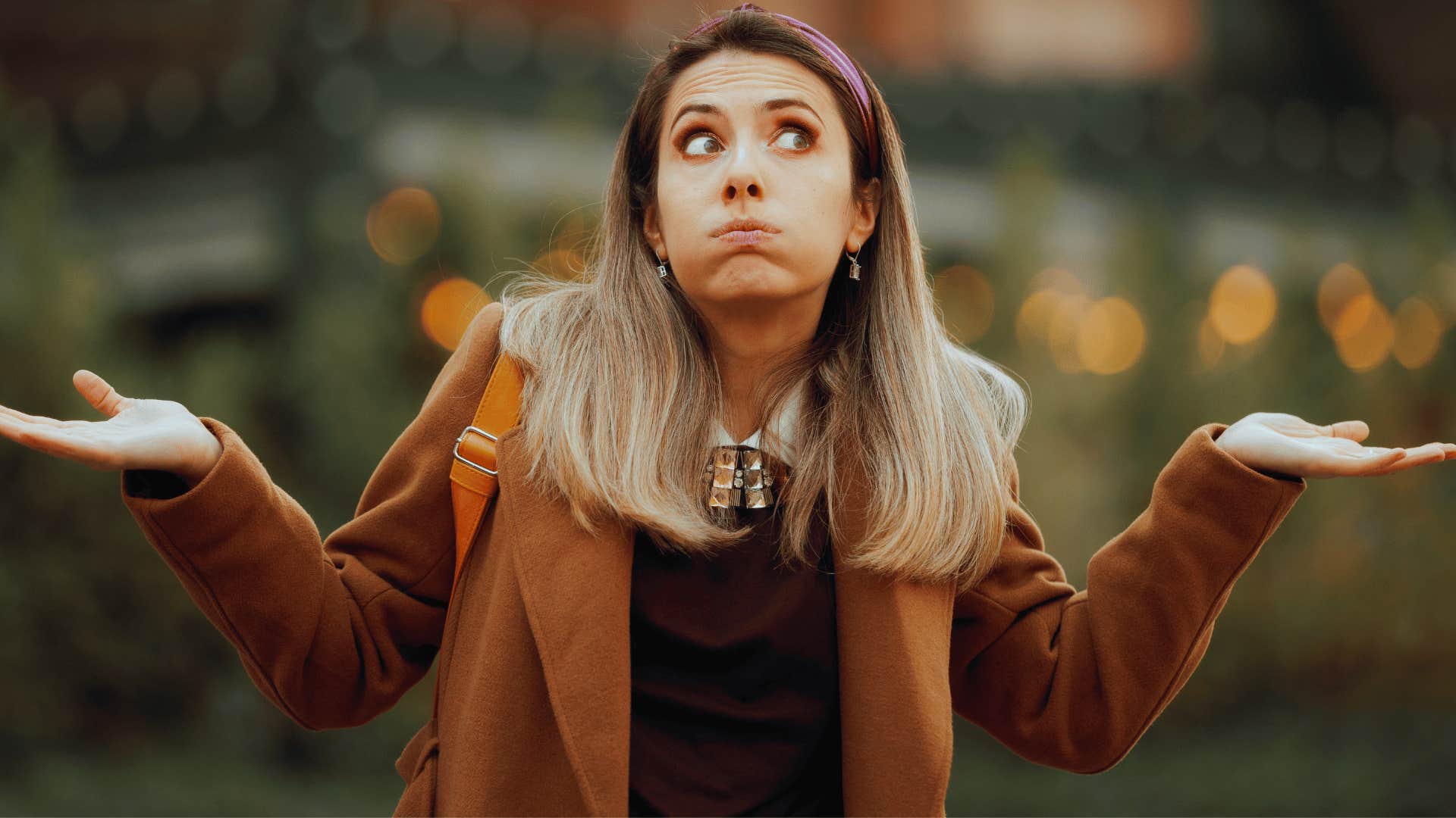 woman in brown coat shrugging as she thinks they'll get over it