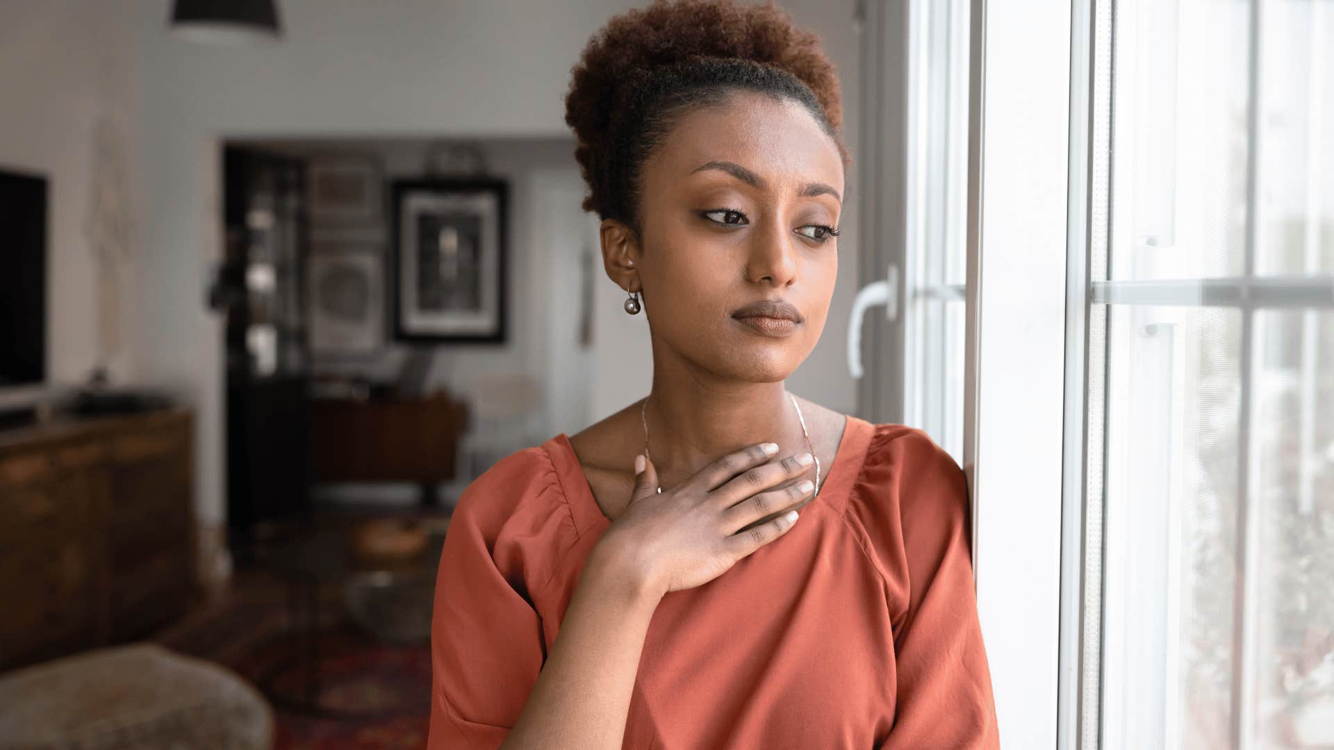 woman putting hand over heart looking outside thinking you can't trust anybody
