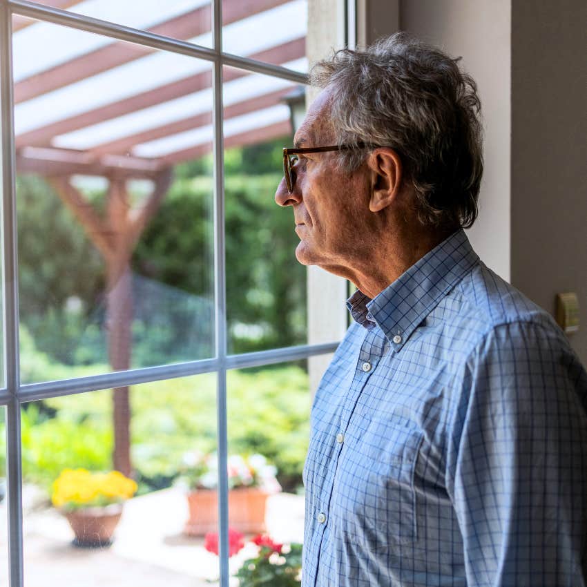 man looking at his bird feeders through living room window