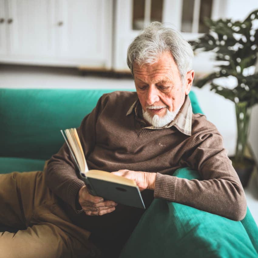 man sitting in his living room reading a book from his personal library