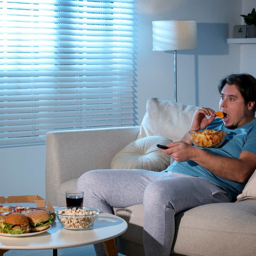 man ignoring his physical health eating chips on the couch