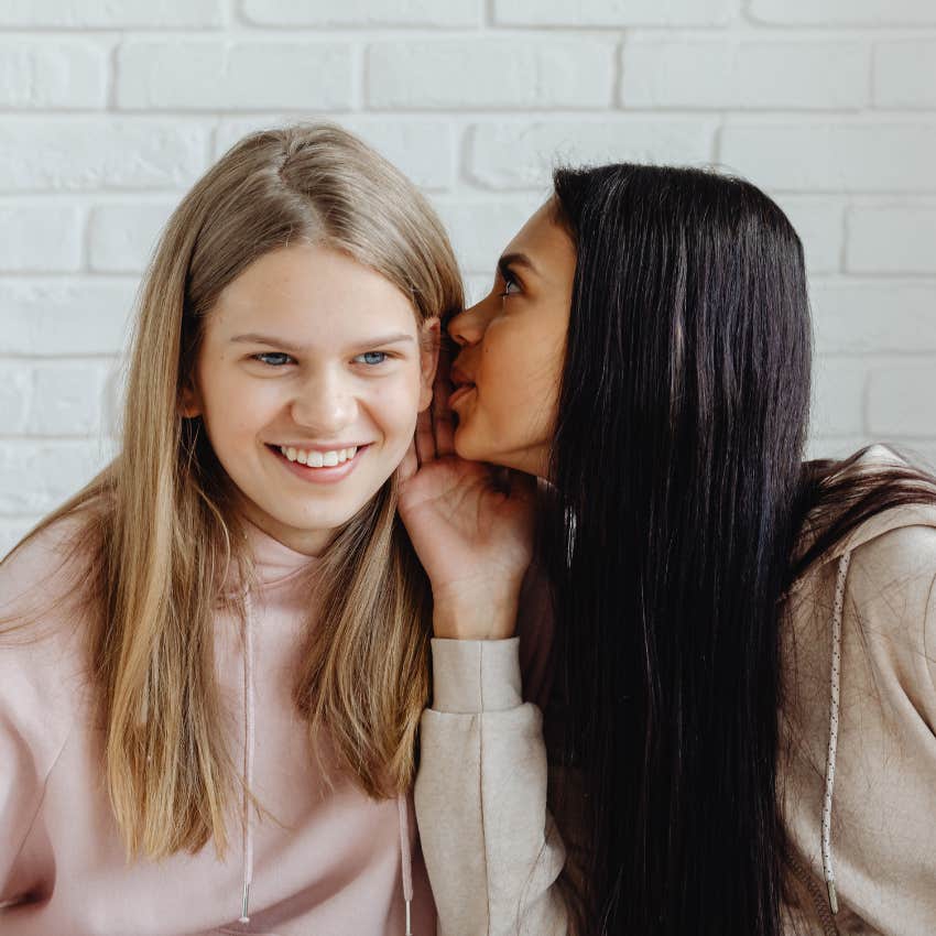woman whispering did you hear in her friends ear