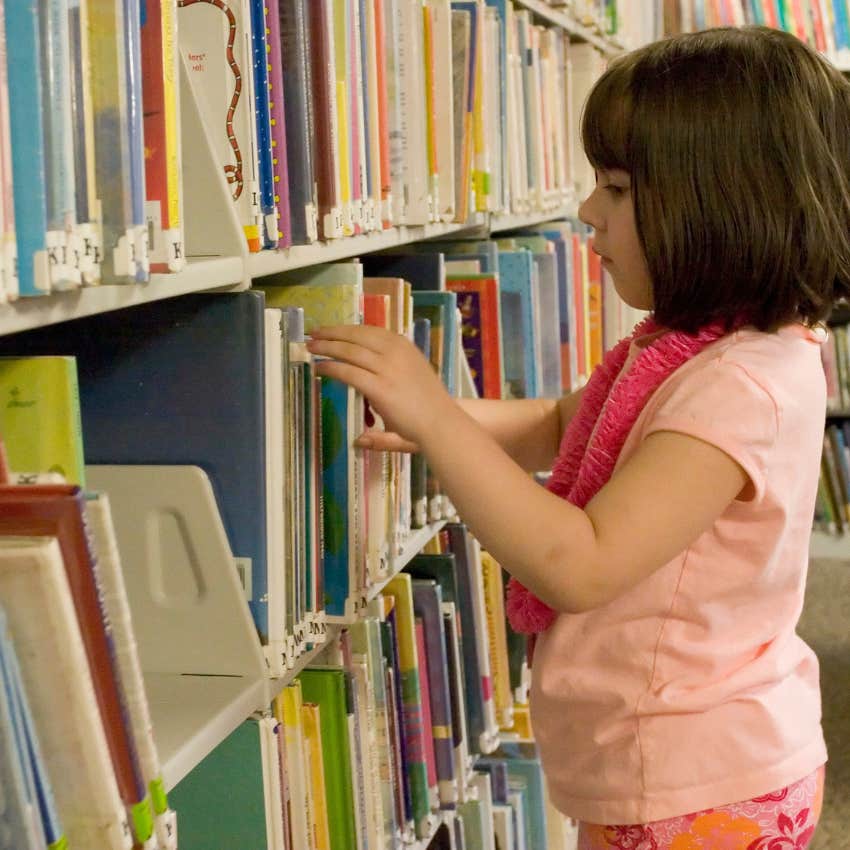 young girl looking at books doing research at the library