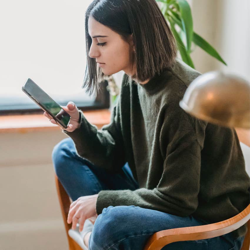 Young woman hunched over her phone with her head tilted forward, showing the posture associated with prolonged scrolling