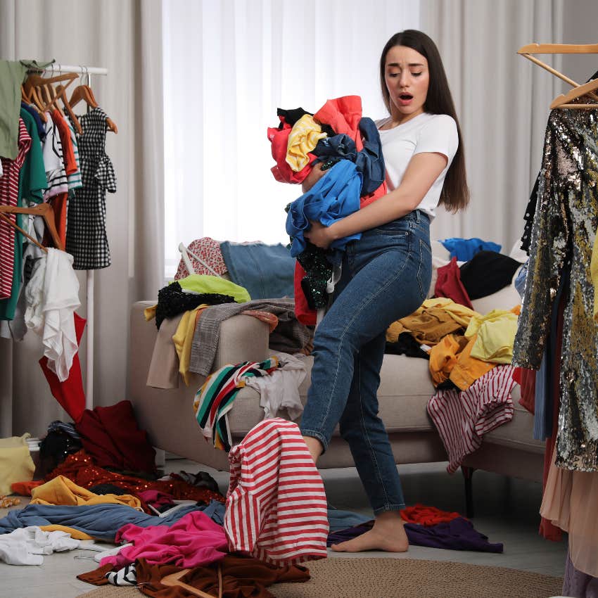 woman with a lot of clothing struggling to carry it