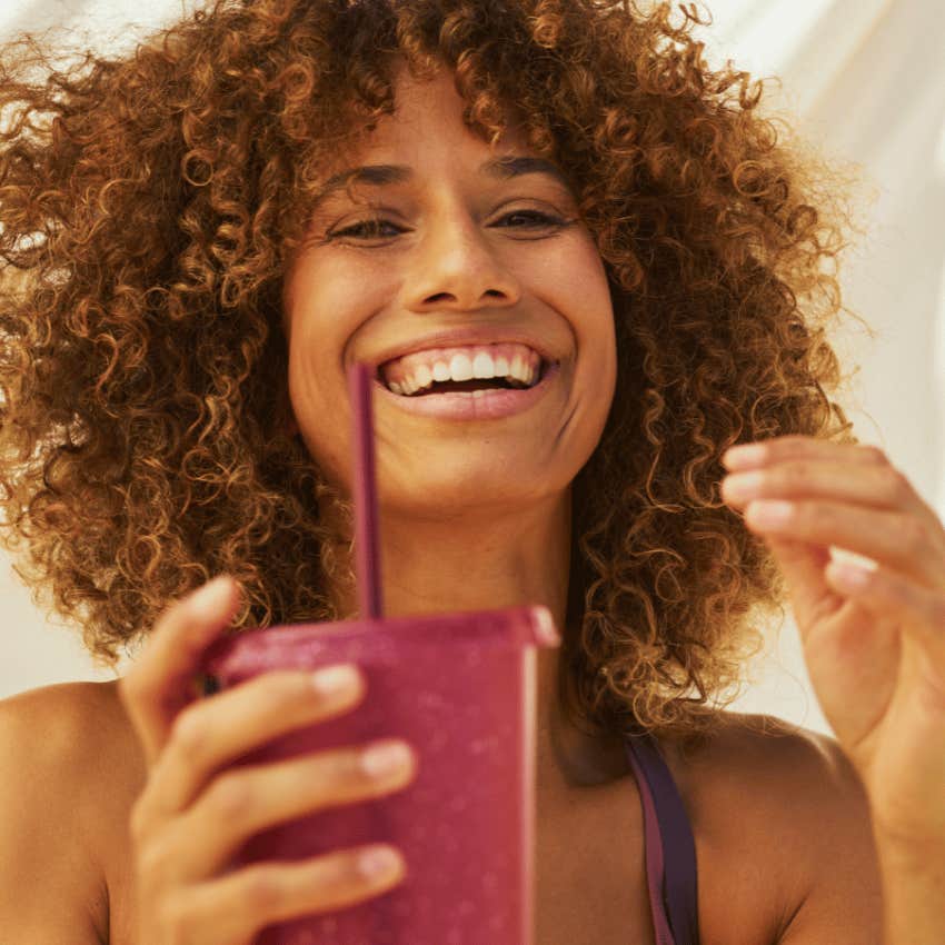 smiling woman holding up fruit smoothie