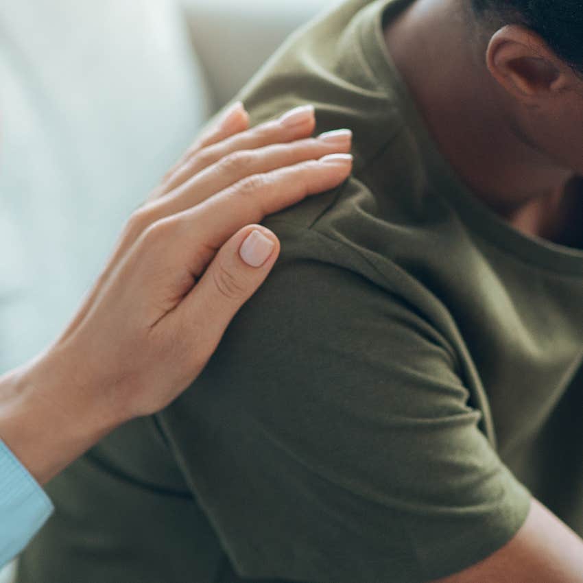 woman putting supporting hand on man's shoulder