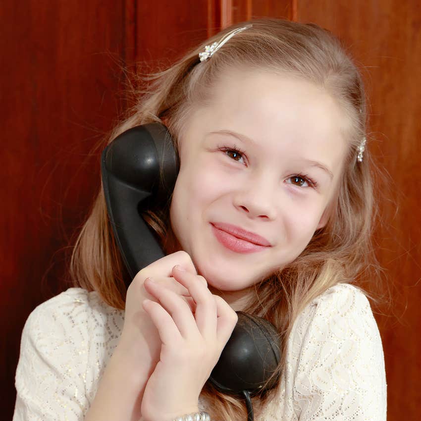 young girl using landline phone on her own