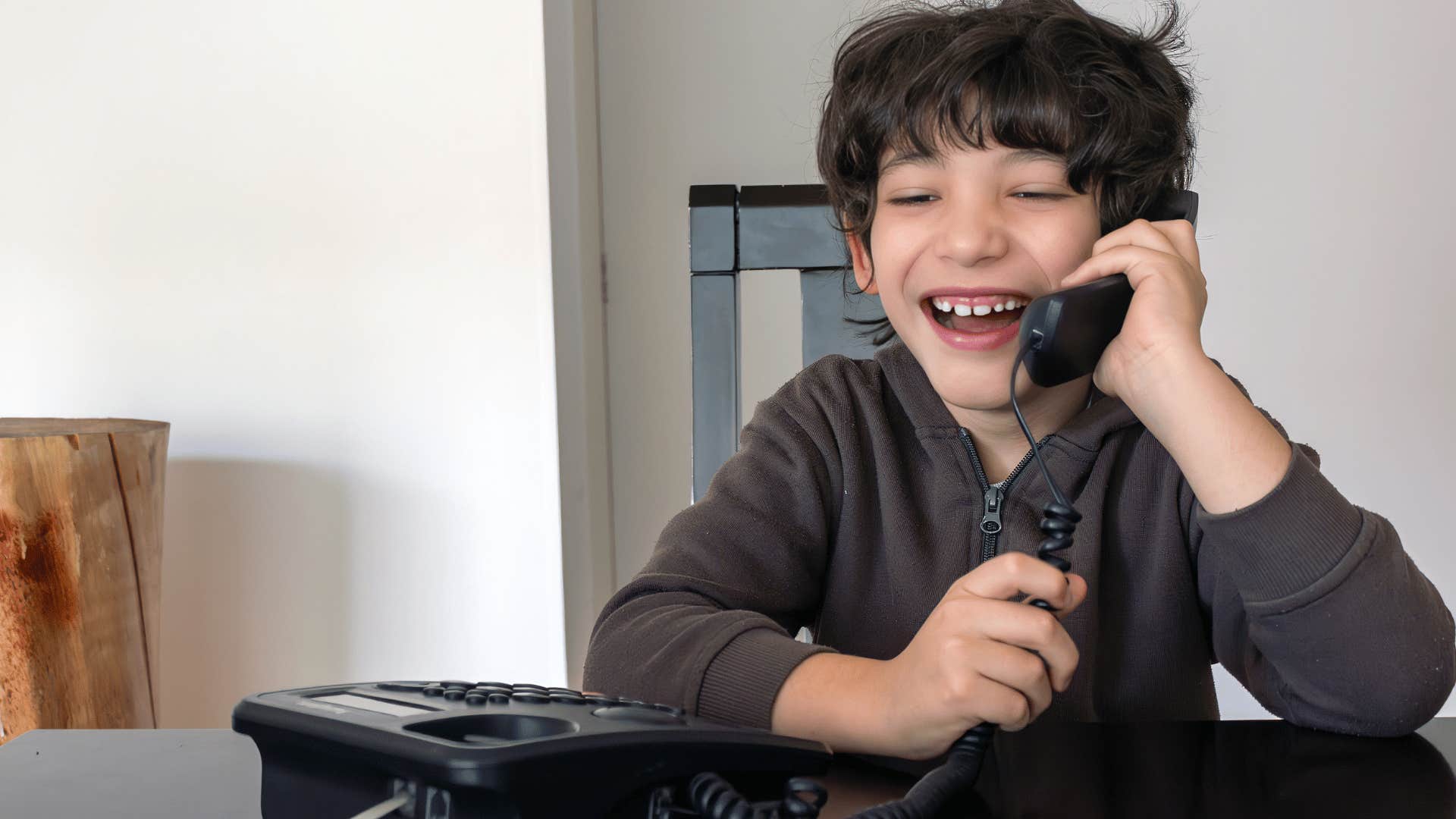 kid using a landline phone to call someone