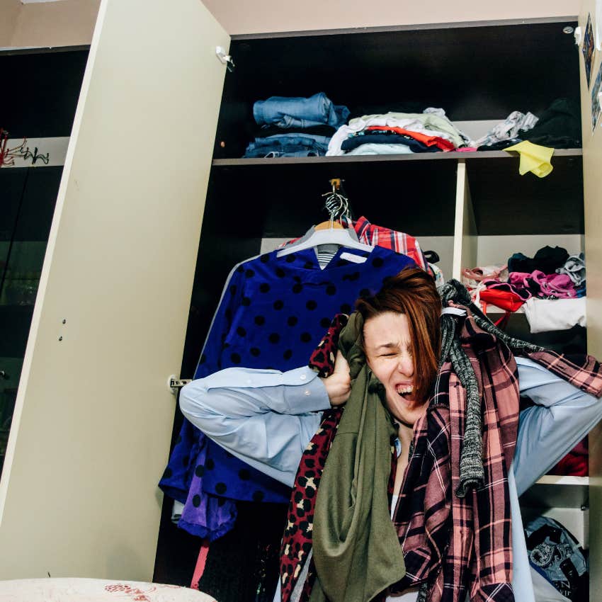 woman in closet that's overcrowded with clothes