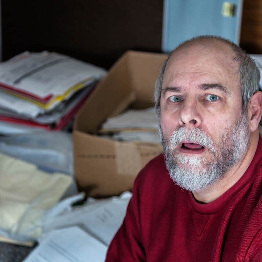man in a cluttered space surrounded by documents