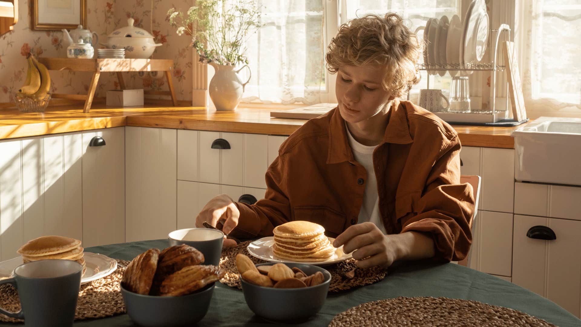 teenage boy sitting at table eating after cooking for himself