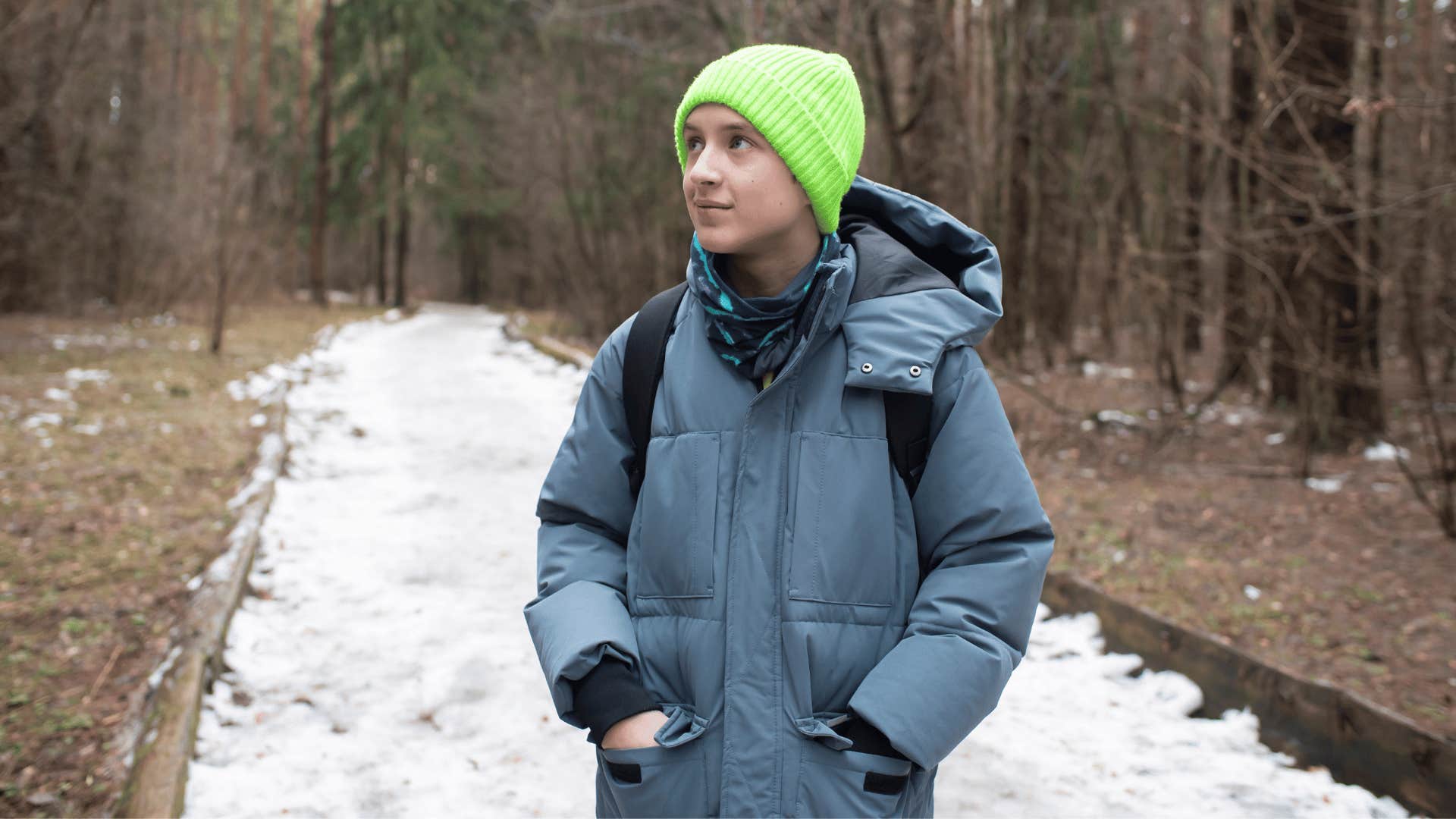 boy exploring the woods and train tracks in the snow
