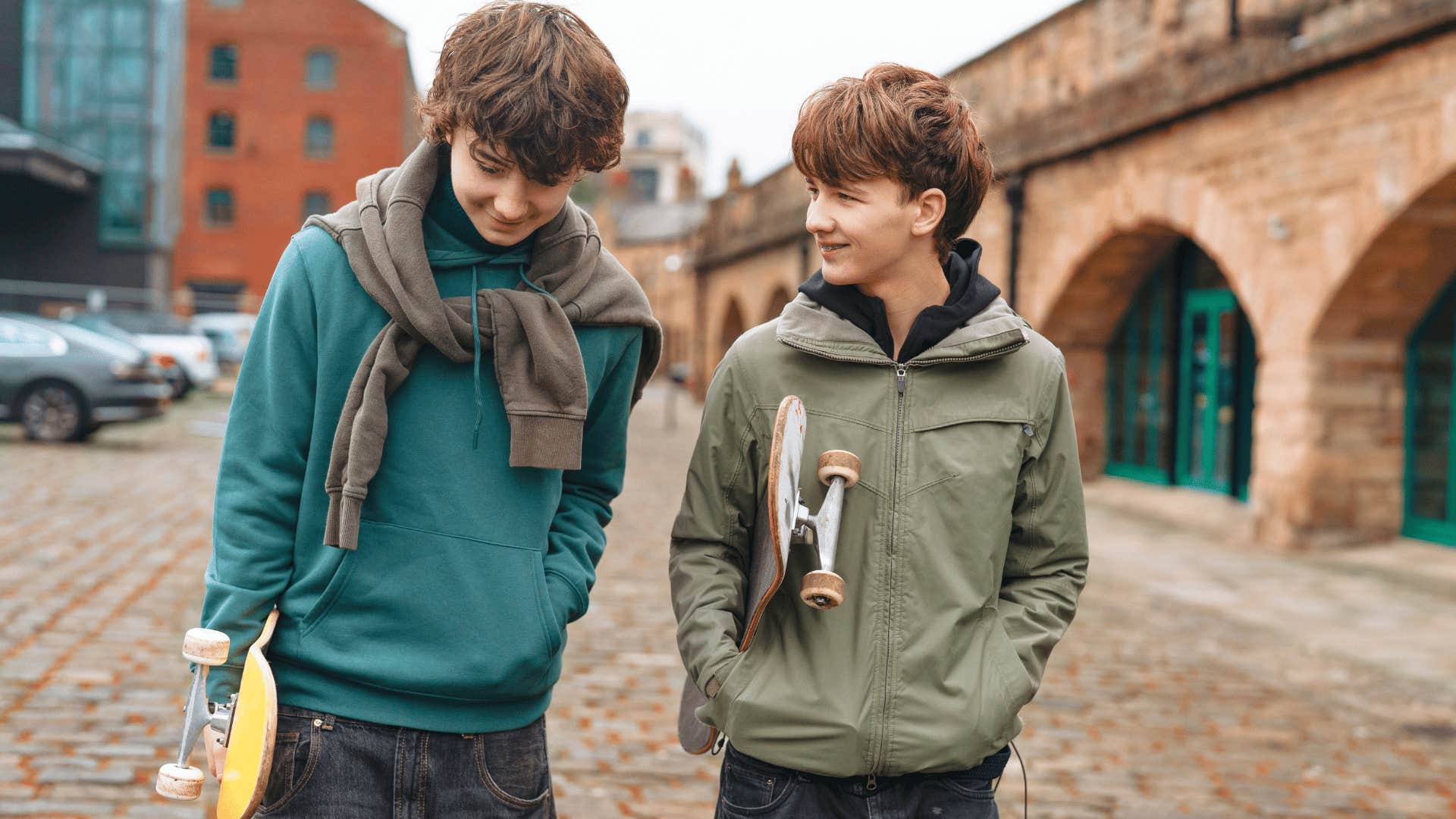 two young boys leaving the house together with skateboards